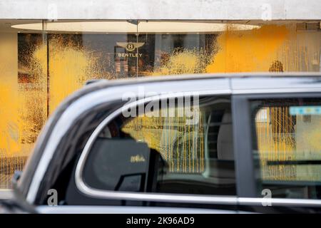 Ein schwarzes Taxi passiert die Folgen eines gezielten Farbstoffangriffs auf die Frontscheiben des Bentley Autohändlers Jack Barclay, der von der Klimaschutzkampagne „Just Stop Oil“ in der Bruton Street in Mayfair am 26.. Oktober 2022 in London, England, durchgeführt wurde. Stockfoto