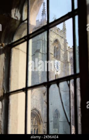 Blick auf den Uhrturm des Minsters von King's Lynn, die Priory Church of Saint Margaret durch ein altes, vielfarbiges Fenster des Rathauses, Großbritannien Stockfoto