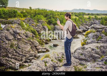 Mann Tourist auf dem Hintergrund der malerischen Niagarafälle auf dem Fluss Cievna. Montenegro, in der Nähe von Podgorica. Reisen Sie durch Montenegro Konzept Stockfoto