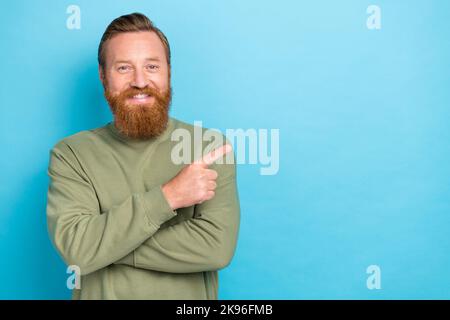 Porträt der guten Laune schöner Kerl mit Ingwer Frisur tragen khaki Pullover Anzeige leeren Raum isoliert auf türkisfarbenem Hintergrund Stockfoto