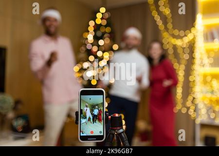 Lustige Freunde record reels Geschichten Front Smartphone Kamera für soziale Netzwerke während der Silvesterfeier Heiligabend Feier. Mit Spaß tanzen Blick Pose bei der Kamera zu Hause Jungs Spaß haben Stockfoto