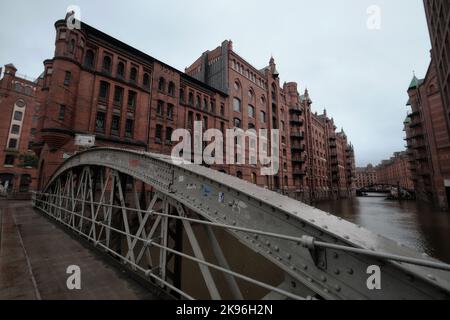 Hamburg, Deutschland - September 2022: Pflastersteinpflaster und Bogenbrücke über Kanäle in der Speicherstadt mit alten Backsteinlagerhäusern Stockfoto