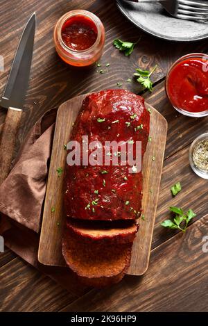 Hackbraten mit Glasur auf Schneidebrett auf Holzhintergrund. Draufsicht, flach liegend Stockfoto