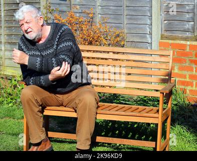 Älterer oder älterer Mann mit Schmerzen, der an Arthritis des Ellenbogens und Armes leidet. Stockfoto