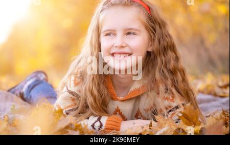 Kind liegt auf Herbstblättern Stockfoto