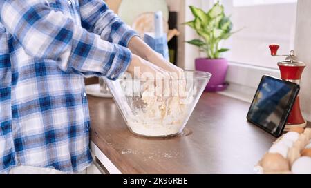 Eine Nahaufnahme der Hände, die in der Küche einen Teig machen Stockfoto