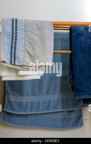 Die hölzerne Wäscheleine mit dem Handtuch und Jeans und Männershorts nahe der weißen Wand im Schlafzimmer des Stadthauses, Vorderansicht mit dem Kopierraum. Stockfoto