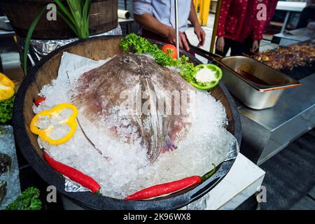 Ein großer frischer Stingray in einem Eisfass liegt im Restaurant. stingray Fisch auf Eis bereit, auf dem traditionellen Markt zu verkaufen. Stockfoto