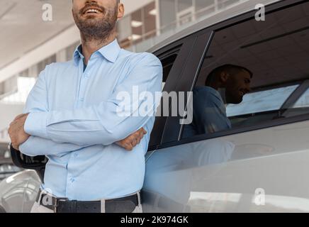 Nahaufnahme eines männlichen Beraters in der Autoschau, der in der Nähe von Autos steht Stockfoto