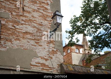 Schöne Aussicht auf eine Straßenecke von Toulouse, mit einem Kirchturm in der Ferne. Das Alte Toulouse. Stockfoto