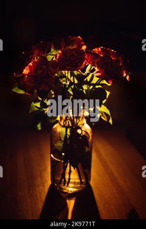 Dunkle launische Blumen rote Rosen Blumenstrauß Hintergrund. Rosa-Banner mit dunklem Blumenmuster. Mystische tiefrote lila Blume auf schwarzem Hintergrund Stockfoto