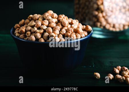Getrocknete Kichererbsen in einer Holzschüssel auf einem Holzhintergrund. Stockfoto