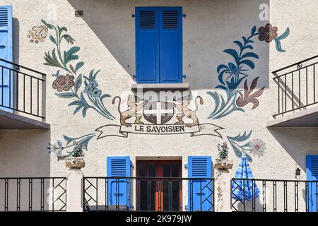 Detail einer Wanddekoration auf der façade eines Gebäudes im Zentrum der Alpenstadt mit einem Wappen, umgeben von Blumen, Chamonix, Frankreich Stockfoto