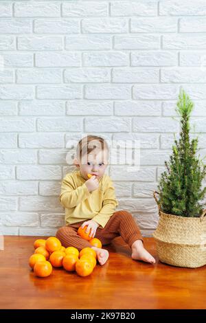 Niedliches lächelndes Kind, das eine frische, saftige Mandarine isst Stockfoto