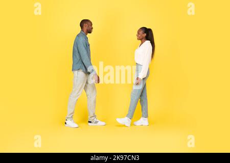 Glücklicher Afroamerikanischer Mann Und Frau, Die Über Gelben Hintergrund Laufen Stockfoto