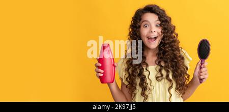 Schockiert Kind lockiges Haar halten Kamm und Shampoo-Flasche. Teen Schönheit Frisur. Kid girl Haarpflege, horizontales Poster. Banner-Kopfzeile mit Kopierbereich. Stockfoto
