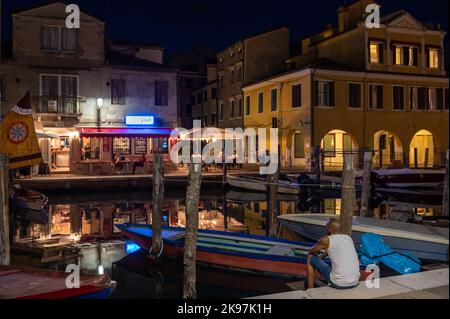 20. August 2022, chioggia, Italien: Touristen genießen die Sommerabende auf den Terrassen der Restaurants entlang des Kanals von Chioggia in Venetien. Chioggia, eine Stadt in der venezianischen Lagune, die viele Touristen beherbergt, die Venedig besuchen, wurde nicht in den venezianischen Stadtkern aufgenommen. Touristen, die dort bleiben, müssen die Steuer jedes Mal zahlen, wenn sie Venedig ab dem 16. Januar 2023 besuchen. (Bild: © Laurent Coust/SOPA Images via ZUMA Press Wire) Stockfoto