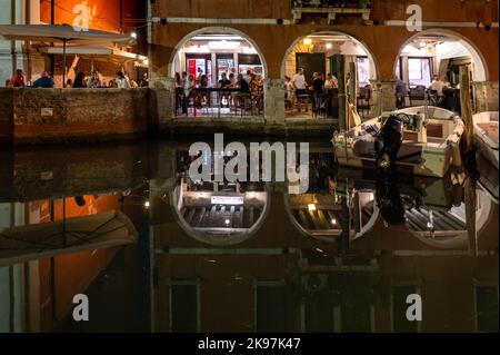 20. August 2022, chioggia, Italien: Touristen genießen die Sommerabende auf den Terrassen der Restaurants entlang des Kanals von Chioggia in Venetien. Chioggia, eine Stadt in der venezianischen Lagune, die viele Touristen beherbergt, die Venedig besuchen, wurde nicht in den venezianischen Stadtkern aufgenommen. Touristen, die dort bleiben, müssen die Steuer jedes Mal zahlen, wenn sie Venedig ab dem 16. Januar 2023 besuchen. (Bild: © Laurent Coust/SOPA Images via ZUMA Press Wire) Stockfoto