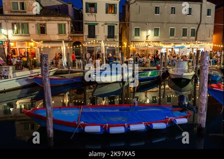 20. August 2022, chioggia, Italien: Touristen genießen die Sommerabende auf den Terrassen der Restaurants entlang des Kanals von Chioggia in Venetien. Chioggia, eine Stadt in der venezianischen Lagune, die viele Touristen beherbergt, die Venedig besuchen, wurde nicht in den venezianischen Stadtkern aufgenommen. Touristen, die dort bleiben, müssen die Steuer jedes Mal zahlen, wenn sie Venedig ab dem 16. Januar 2023 besuchen. (Bild: © Laurent Coust/SOPA Images via ZUMA Press Wire) Stockfoto