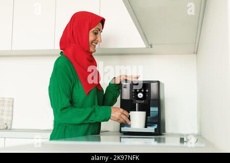 Glücklich Reif Muslimische Frau Mit Kaffeemaschine In Der Küche Stockfoto
