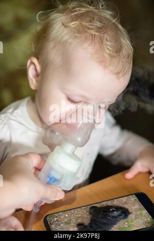 Inhalation macht das Kind zu Hause. Medikamentöse Behandlung von Disspiratorerkrankungen mit Vernebler. Stockfoto