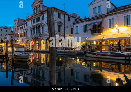 20. August 2022, chioggia, Italien: Touristen genießen die Sommerabende auf den Terrassen der Restaurants entlang des Kanals von Chioggia in Venetien. Chioggia, eine Stadt in der venezianischen Lagune, die viele Touristen beherbergt, die Venedig besuchen, wurde nicht in den venezianischen Stadtkern aufgenommen. Touristen, die dort bleiben, müssen die Steuer jedes Mal zahlen, wenn sie Venedig ab dem 16. Januar 2023 besuchen. (Bild: © Laurent Coust/SOPA Images via ZUMA Press Wire) Stockfoto