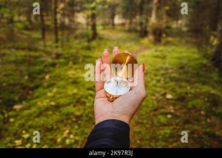 Hand mit Kompass in Waldgebiet. POV Reisekonzept Stockfoto