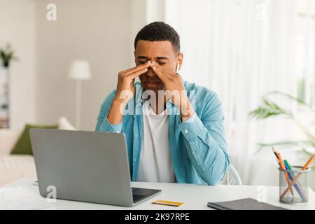 Traurige müde junge schwarze Männer ruhen von der Arbeit mit Laptop, leiden an Migräne Stockfoto