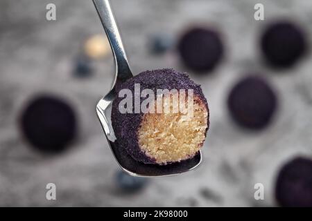 Hausgemachte Trüffel. Runde Süßigkeiten. Trüffel eine Mandeln. Vegetarische Trüffel gefüllt mit Mandeln und Heidelbeere auf grauem Hintergrund Stockfoto