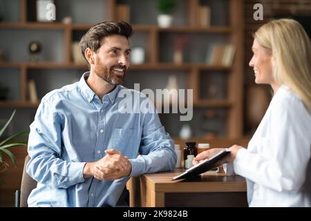 Hübscher Mann Im Gespräch Mit Der Ärztin Während Der Verabredung Im Büro Stockfoto