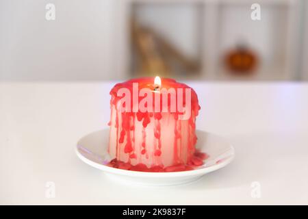 DIY Halloween Halloween weiße Kerze, bedeckt mit rotem Wachs wie Bluttropfen auf weißem Hintergrund. Geschenkidee, Dekor für Halloween. Schritt für Schritt. Blutige Kerzen Halloween Urlaub. Workshop. Stockfoto