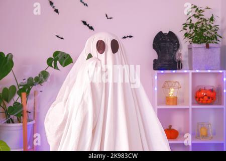 Der Halloween-Geist verwendet ein Mobiltelefon für Anrufe, Glückwünsche, Einschüchterung. Der Geist macht an Halloween eine Bestellung von einem Smartphone. Witziges Halloween-Konzept. Neonlicht. Stockfoto