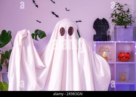 Der Halloween-Geist verwendet ein Mobiltelefon für Anrufe, Glückwünsche, Einschüchterung. Der Geist macht an Halloween eine Bestellung von einem Smartphone. Witziges Halloween-Konzept. Neonlicht. Stockfoto