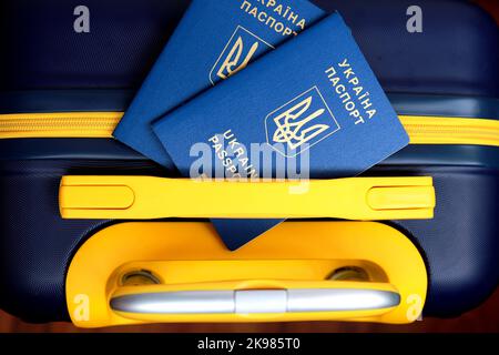 2 Pässe Ukraine mit Inschrift in Ukrainisch - Pass der Ukraine liegen auf gelb-blauen Koffer in der Farbe der ukrainischen Flagge an der Grenze. Reisen Stockfoto