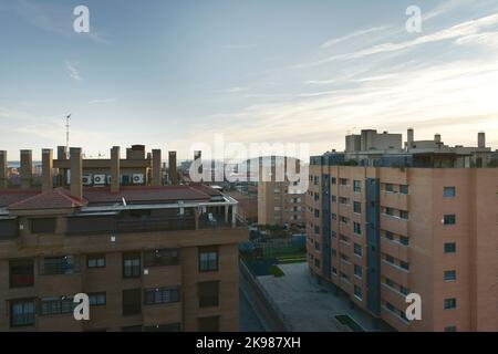 Fassaden städtischer Wohnhäuser mit vielen Schornsteinen und dem Stadion Atlético de Madrid im Hintergrund Stockfoto