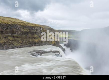 Wasser donnert über den Rand des berühmten Wasserfalls Gullfoss, während Nebel und Sprühnebel aus der Schlucht steigen. Stockfoto