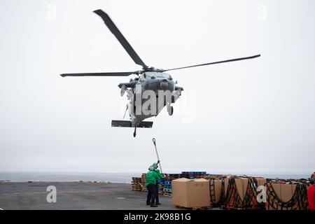 Segler, die dem erstklassigen Frachtführer USS Gerald R. Ford (CVN 78) zugewiesen wurden, bereiten sich darauf vor, während einer vertikalen Auffüllung mit Trockenfracht- und Munitionsschiff USNS Medgar Evers eine Palette von Hilfsgütern an ein MH-60s Knighthawk, das an den 'Tridents' des Helicopter Sea Combat Squadron (HSC) 9 befestigt ist, anzuschließen (T-AKE 13), 24. Oktober 2022. Die Gerald R. Ford Carrier Strike Group (GRFCSG) wird im Atlantischen Ozean eingesetzt und führt Schulungen und Operationen zusammen mit NATO-Verbündeten und -Partnern durch, um die Integration für zukünftige Operationen zu verbessern und das Engagement der US-Marine für eine friedliche, st zu demonstrieren Stockfoto