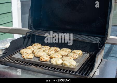 Ein Tablett mit gekochten runden Salzcod Fischkuchen wird auf einem Barbecue zubereitet. Die Mischung aus herzhaften, Kartoffeln, salzhaltigem Kabeljau und Butter wird zu Pasteten geformt. Stockfoto