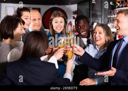 Internationale Gruppe von Geschäftsleuten, die mit Champagner toasten und sich auf der Büroparty im Nachtclub amüsieren Stockfoto