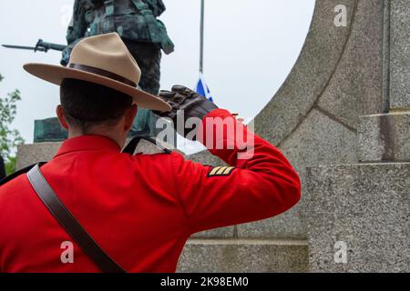 Ein RCMP-Offizier steht während einer Zeremonie vor der Tür und grüßt. Die Uniform von serge ist leuchtend rot. Der Offizier trägt einen hellbraunen Stetson Stockfoto