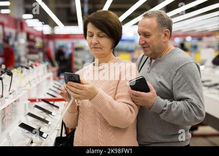 Seniorenpaar, das sich im Technikgeschäft für ein Smartphone entschieden hat Stockfoto