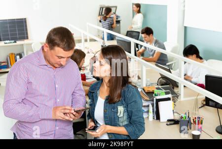 Mitarbeiter im Büro, die sich am Schreibtisch unterhalten Stockfoto