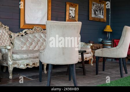 Ein elegantes, knochenweißes, klassisches, gepolstertes chesterfield mit einem Sessel. Die Möbel sind mit einem champagnerfarbenen Stoff mit Knöpfen auf der Rückseite ausgestattet Stockfoto