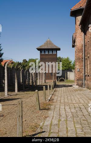 Elektrische Stacheldrahtzäune und Wachturm im ehemaligen Konzentrationslager Auschwitz I, Auschwitz, Polen. Stockfoto