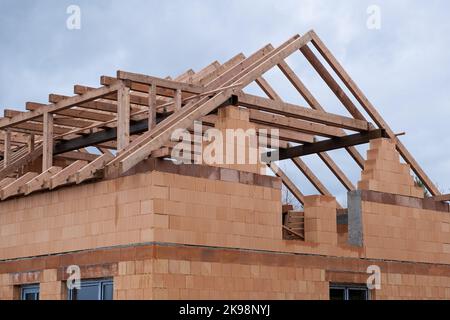 Dachkonstruktion auf der neuen keramischen Ziegelwand, der Beginn der hölzernen Basis für Dach, Holz- und Metallholz. Bauarbeiten, Haus aus Keramik-Block Stockfoto