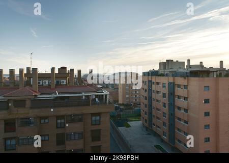 Fassaden städtischer Wohnhäuser mit vielen Schornsteinen und dem Stadion Atlético de Madrid im Hintergrund Stockfoto