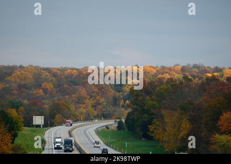 Am 26. Oktober 2022, zwischen Harrisburg und Philadelphia, Pennsylvania, USA, rast der Verkehr am Laub der Bäume vorbei, das in den höchsten Herbstfarben auf der Pennsylvania Turnpike Interstate I-76 liegt. In zwei Wochen gehen die Amerikaner zu den Wahllokalen für die Halbzeitwahlen, deren Ergebnisse massive Auswirkungen auf die Gestalt der Nation haben könnten. Kredit: OOgImages/Alamy Live Nachrichten Stockfoto