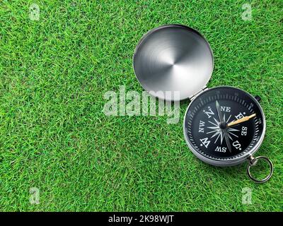 Kompass auf grünem Feld von Gras Hintergrund. Reiseziel und Navigationskonzept Stockfoto