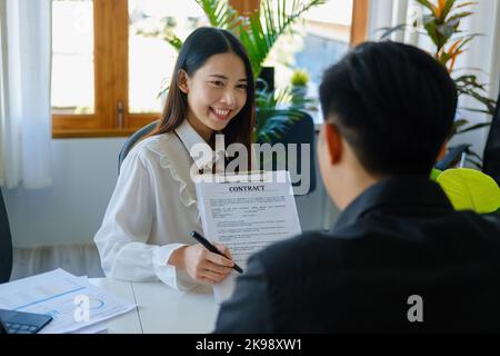 Garantie, Hypothek, Unterzeichnung, Versicherung, Porträt eines Agenten oder Bankangestellte asiatische Frau mit wichtigen Dokumenten für männliche Kunden vor zu lesen Stockfoto