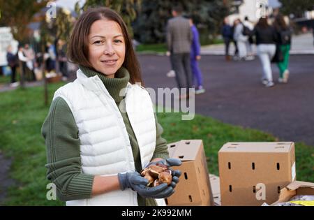 REGION ZAKARPATTIA, UKRAINE - 26. OKTOBER 2022 - Olena Zhuk, die Witwe von Roman Zhuk, die bei der Verteidigung der Ukraine starb, pflanzt Tulpen zu Ehren ihres Mannes in der Tulpenallee. Olena und die von ihr eingeladenen Stadtbewohner pflanzten 13 Tulpen vor der Staatlichen Universität Mukachevo, wo das junge Paar Mukachevo, Region Zakarpattia, Westukraine, getroffen hatte. Stockfoto